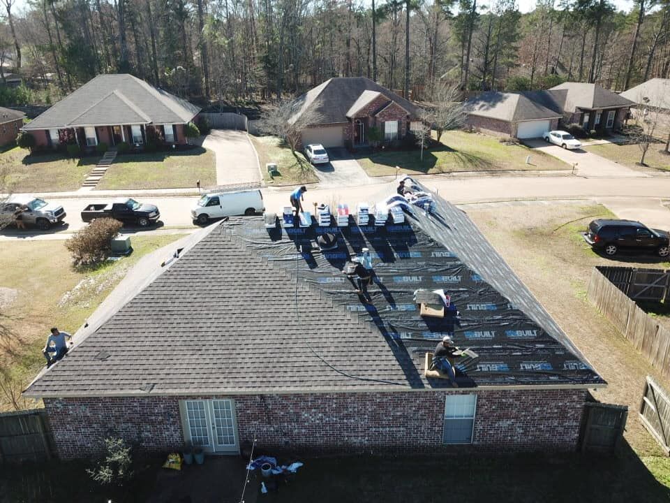 Roofers working on a residential house roof; several workers, sunny day, neighborhood setting.