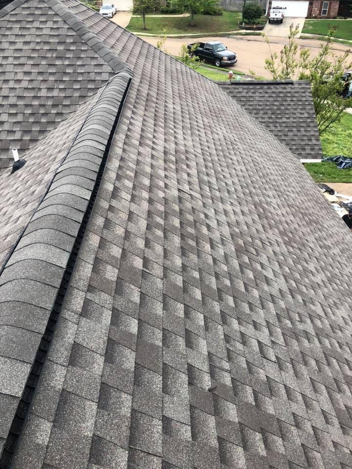 Gray asphalt shingle roof with a ridge, outdoors.