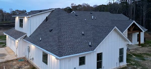 White house with dark gray roof and trees in the background.