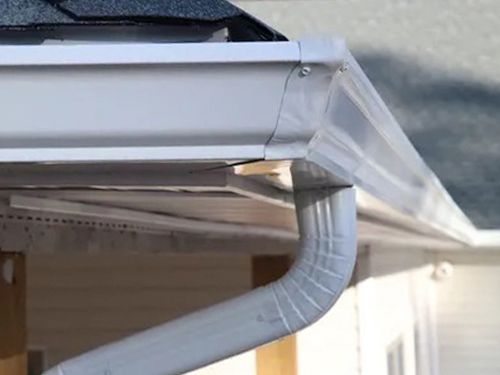 A close up of a white gutter on the side of a house.