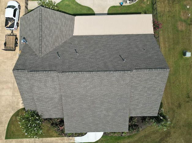 Overhead view of a house with a gray shingle roof, brown metal roof, and a white car in the driveway.