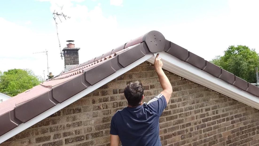 A man is working on the roof of a house.