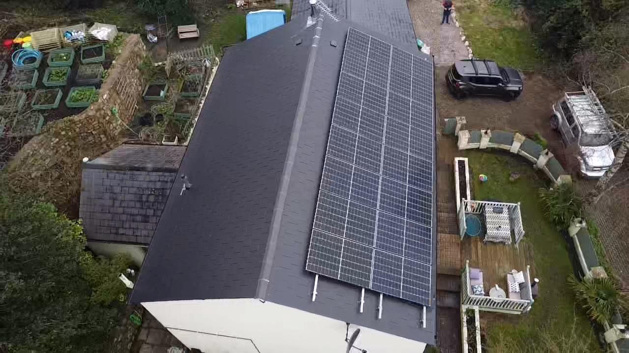 An aerial view of a house with solar panels on the roof.
