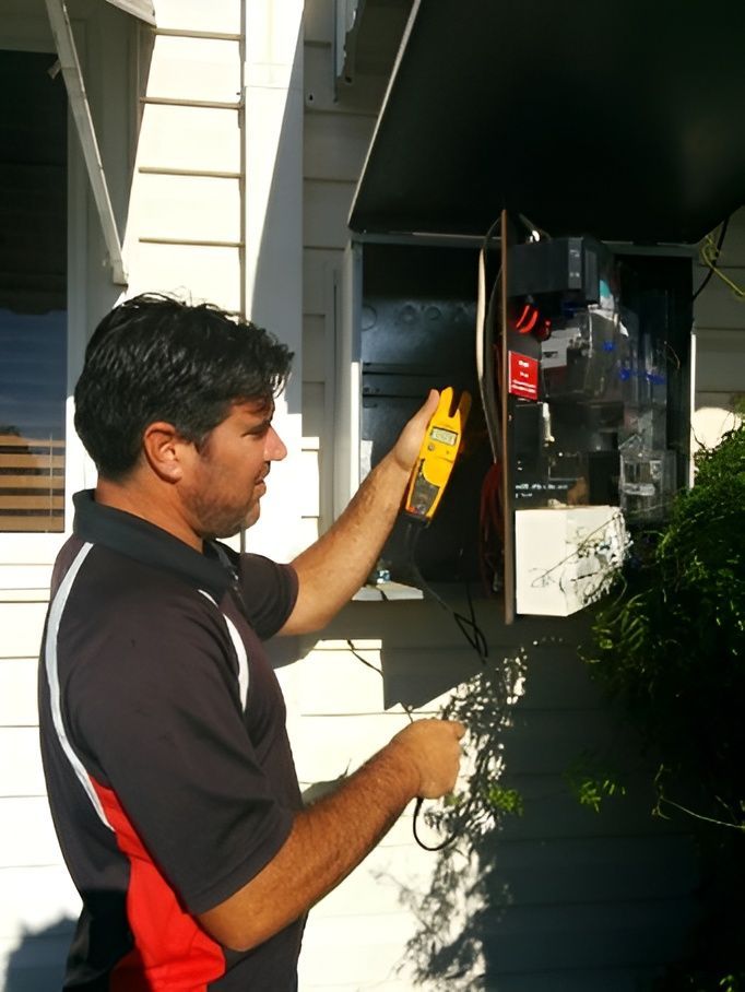 Man in a Red and Black Shirt Using a Tool on an Outdoor Electrical Box — Robert Coony Electrician in Nambucca Heads, NSW