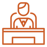 Person behind a desk, wearing a tie, in an office setting.