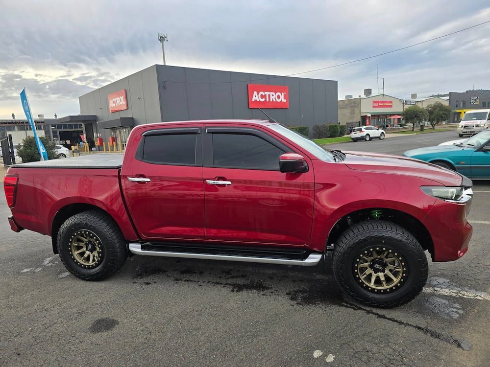 A Red Truck is Parked in a Parking Lot in Front of a Building — Peel Valley Tyres in Armidale, NSW