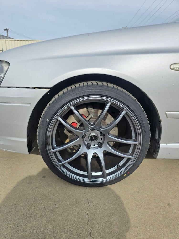 A Silver Car With Black Wheels and Tires is Parked on the Side of the Road — Peel Valley Tyres in Murrurundi, NSW