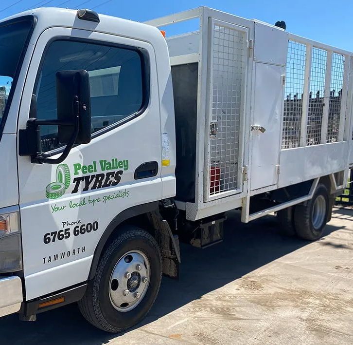 White Peel Valley Tyres truck with a caged cargo area, parked on pavement. — Peel Valley Tyres in Murrurundi, NSW
