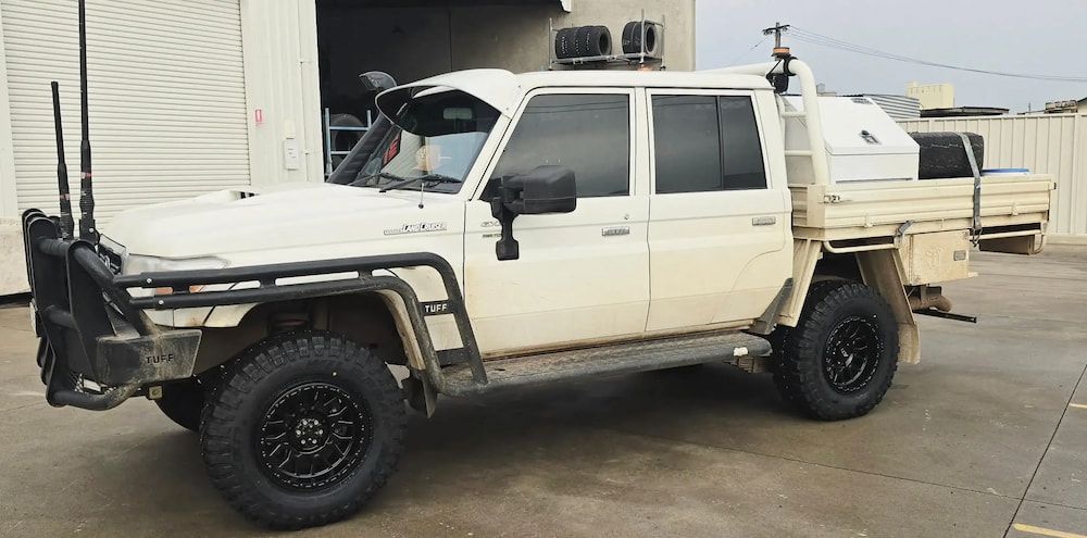 A White Truck With Black Tires is Parked in Front of a Building — Peel Valley Tyres in Taminda, NSW