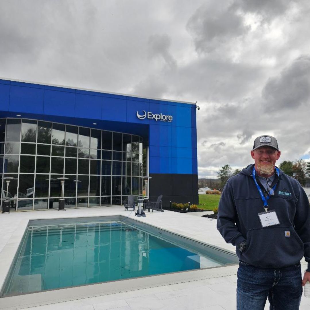Man stands near a blue building with a pool. The building says