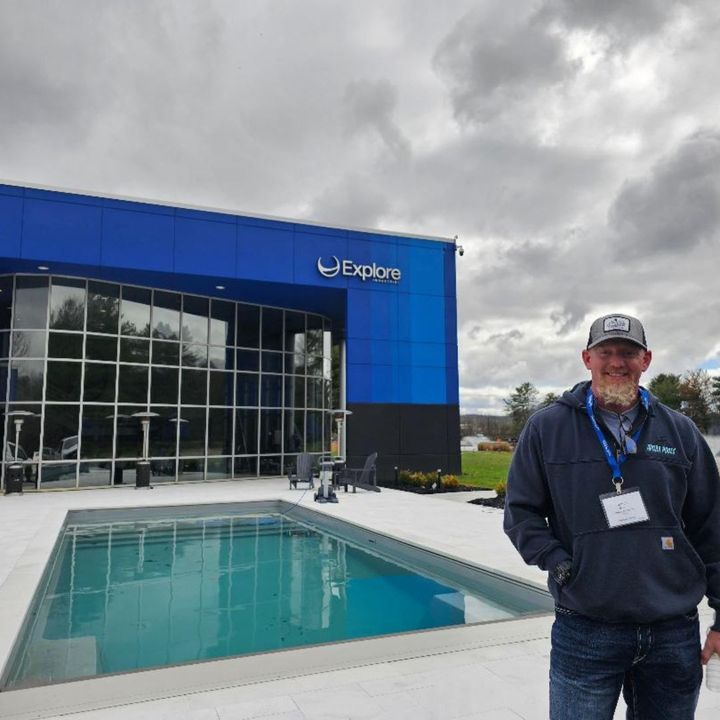 Man stands near a blue building with a pool. The building says 
