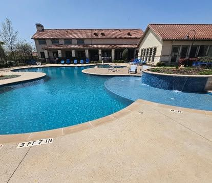 A resort-style swimming pool with buildings in the background on a sunny day.