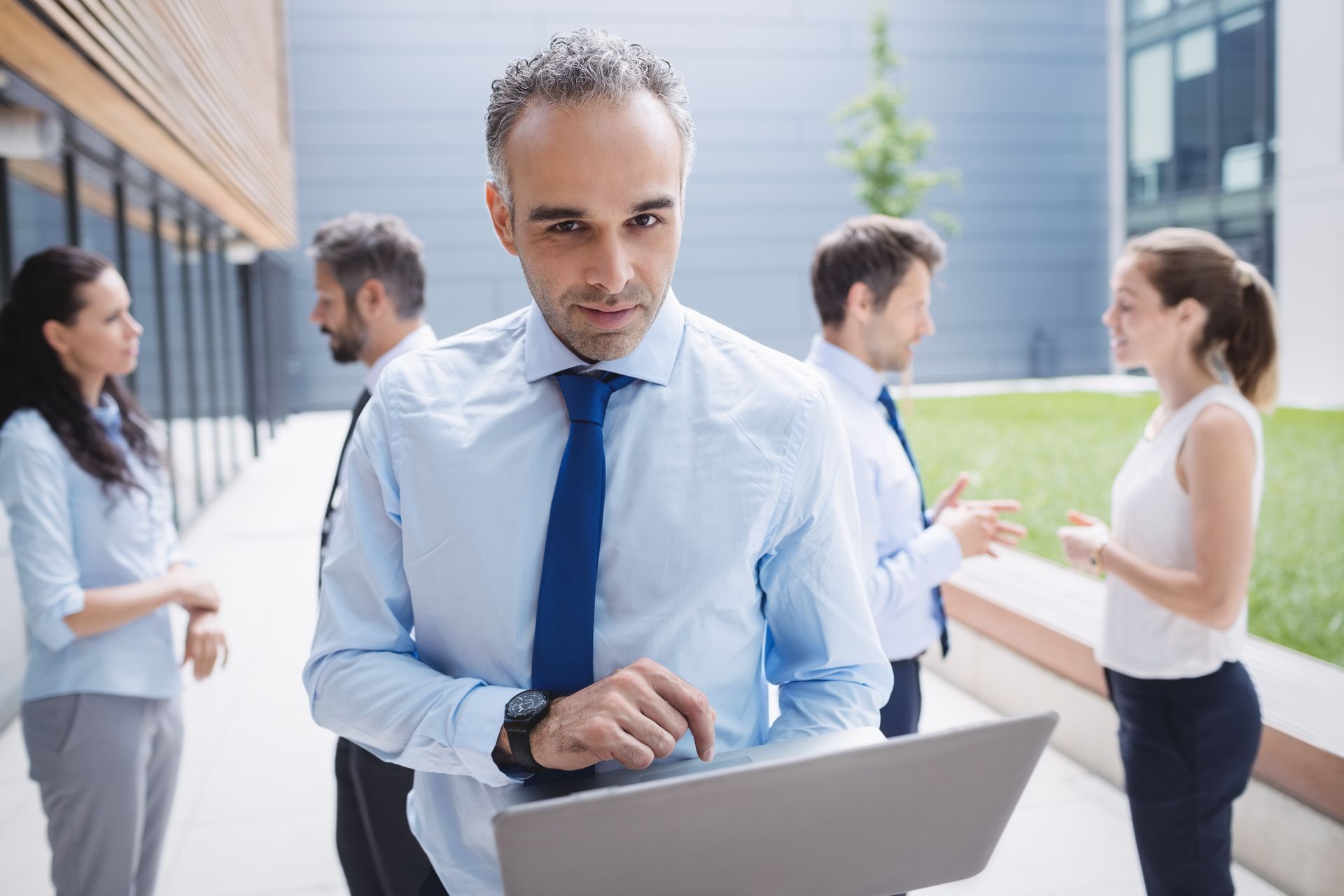 Um homem está usando um laptop em pé na frente de um grupo de pessoas.