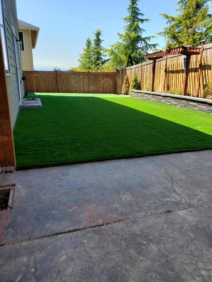 A backyard with a large lawn and a wooden fence.