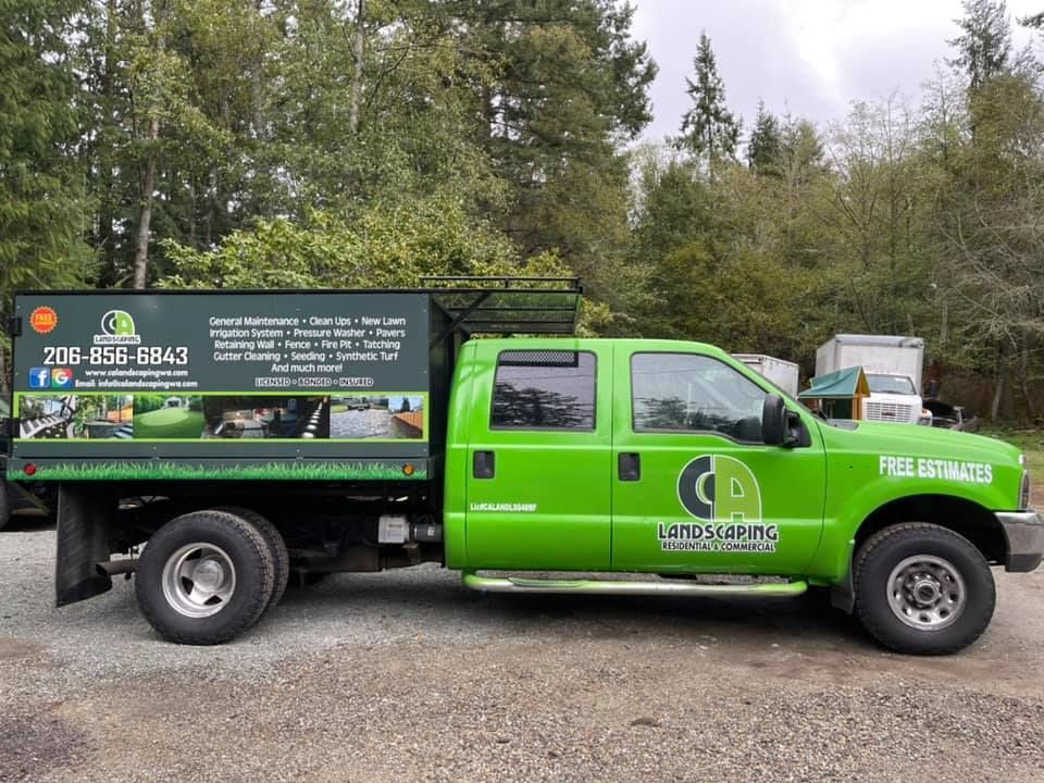 A green truck is parked in a gravel lot.