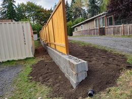 A wooden fence is being built next to a brick wall.