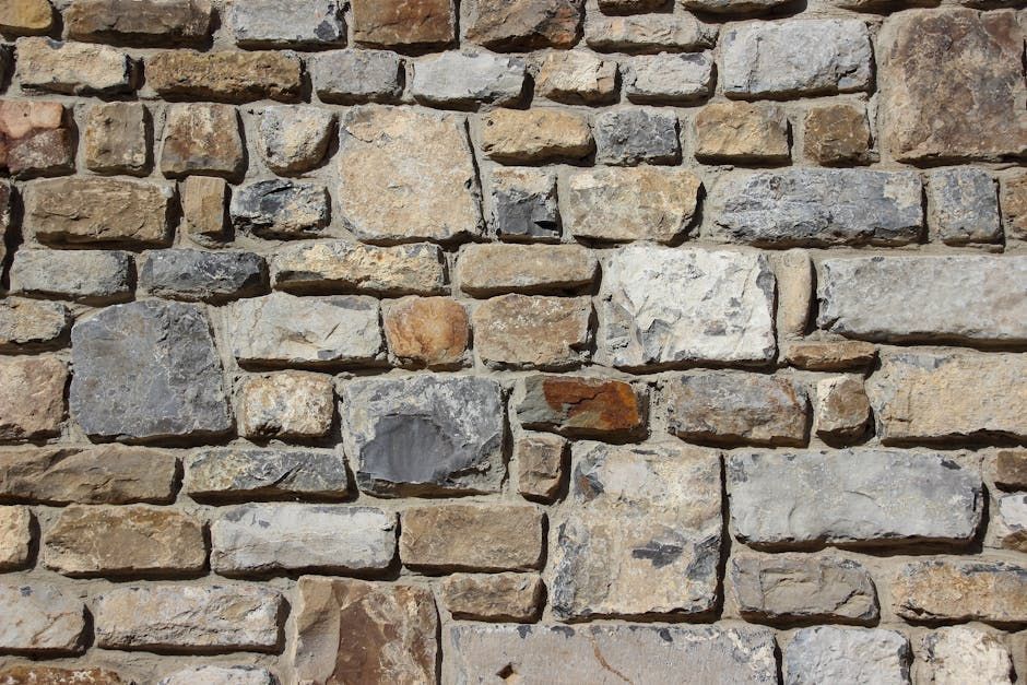 Retaining Stone wall with varied colors and shapes, textures in shades of brown, gray, and beige.