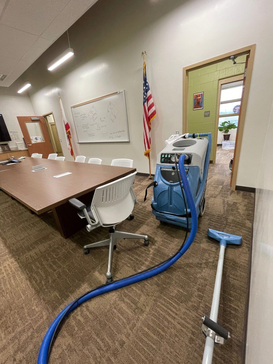 A vacuum cleaner is sitting in a conference room next to a table and chairs.