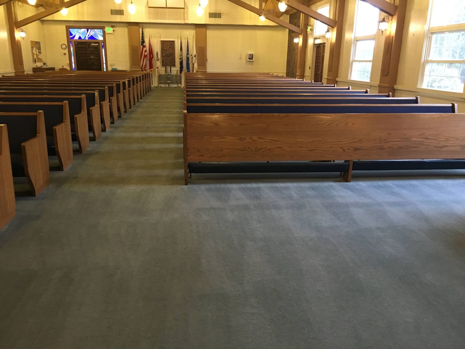 A church with rows of wooden benches and a carpeted floor.