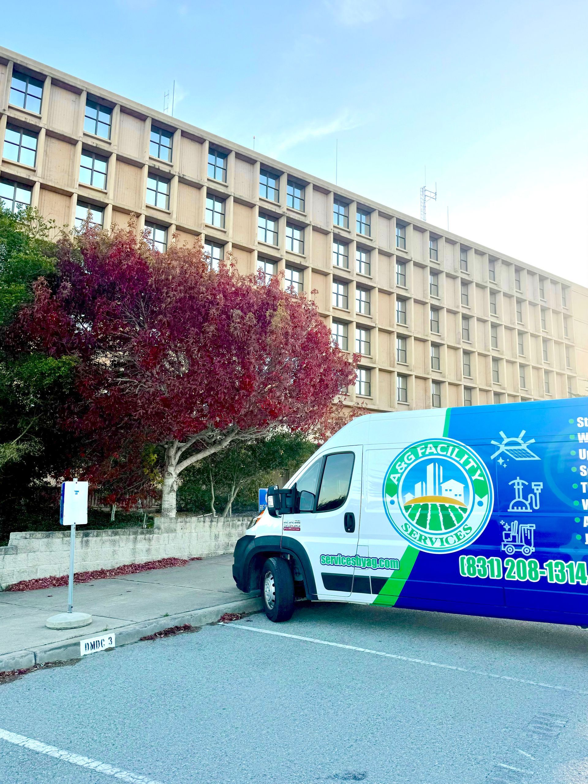 A white van is parked in front of a large building.