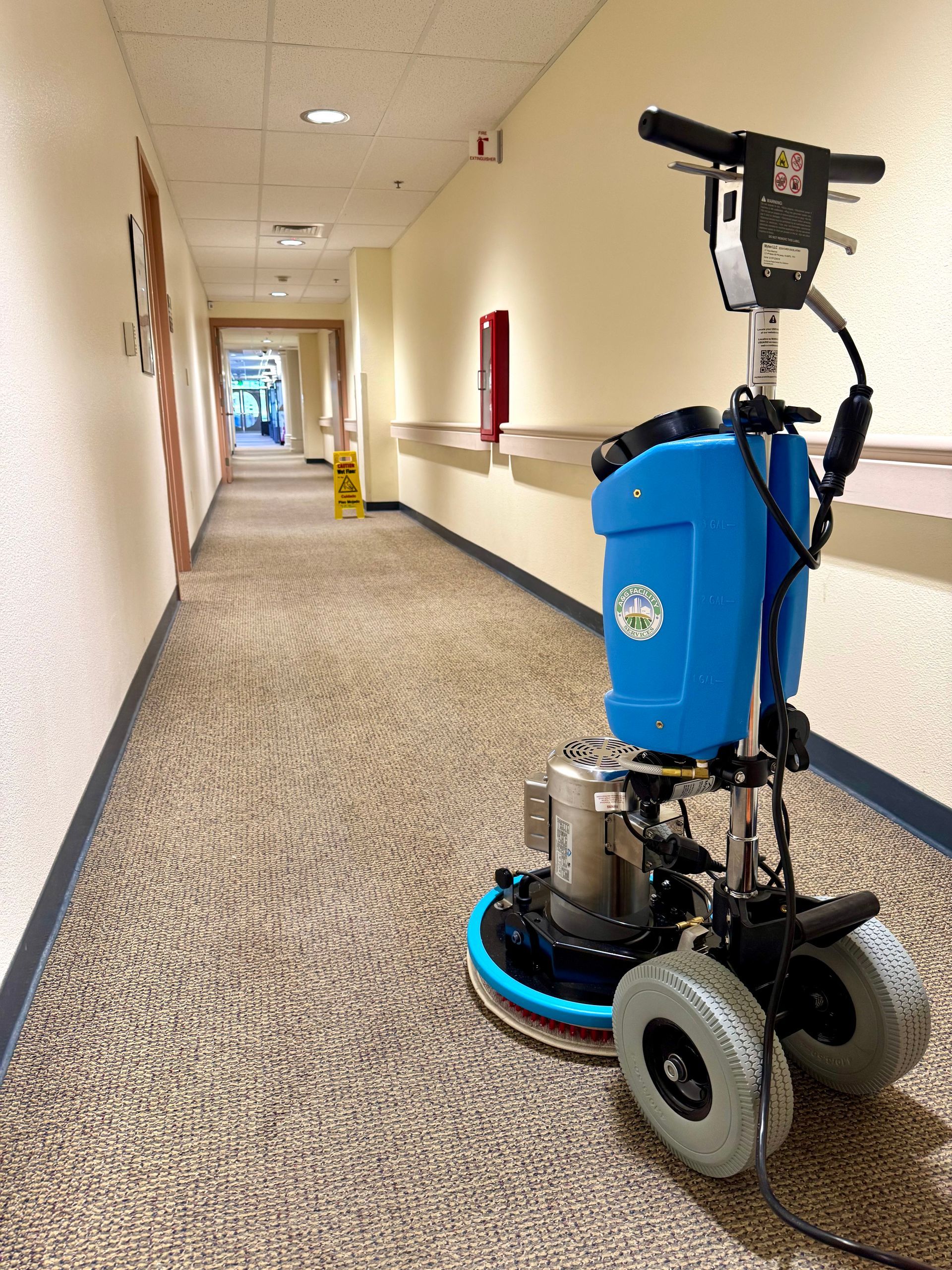 A blue machine is cleaning a carpet in a hallway