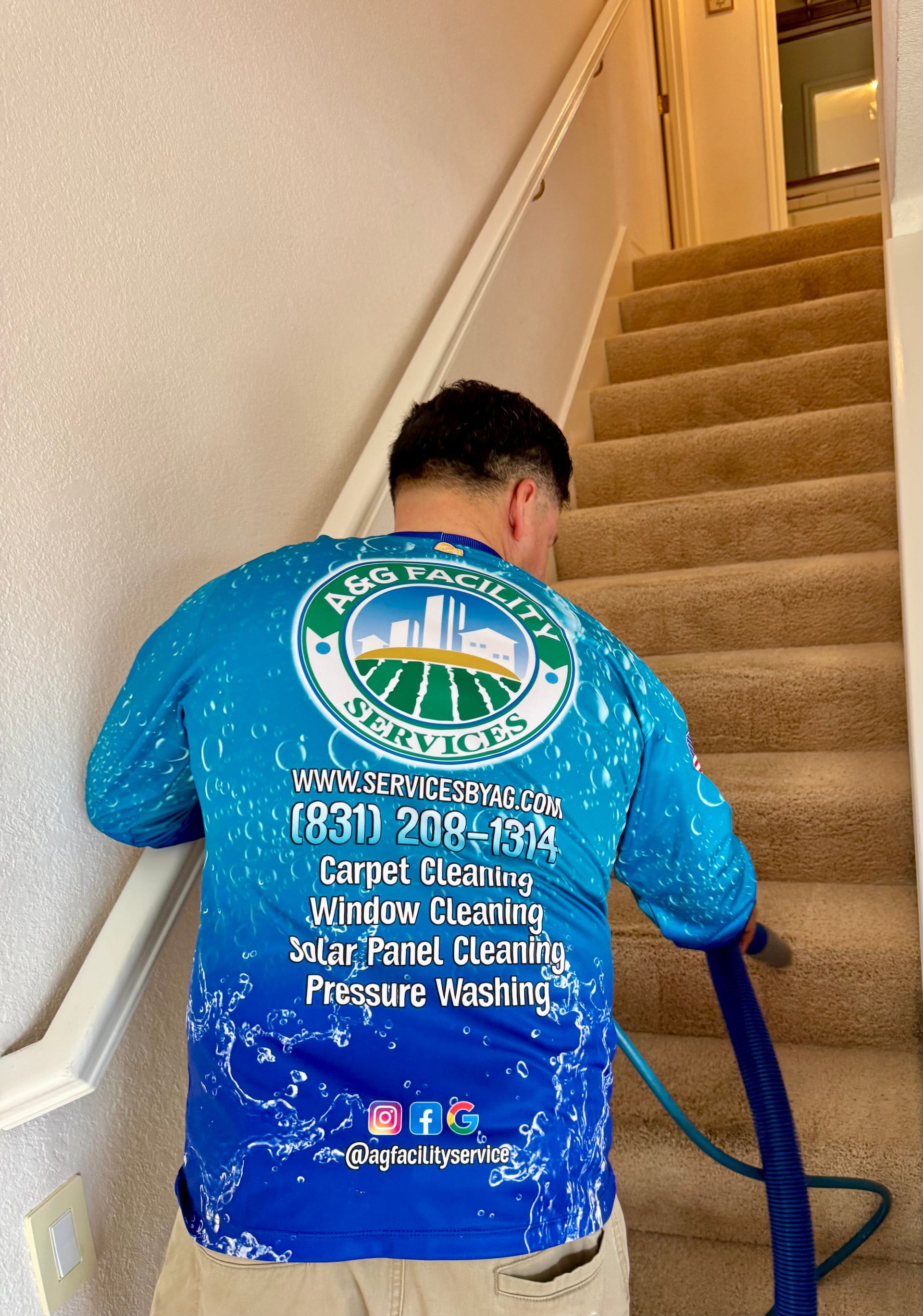 A man in a blue shirt is cleaning stairs with a vacuum cleaner.