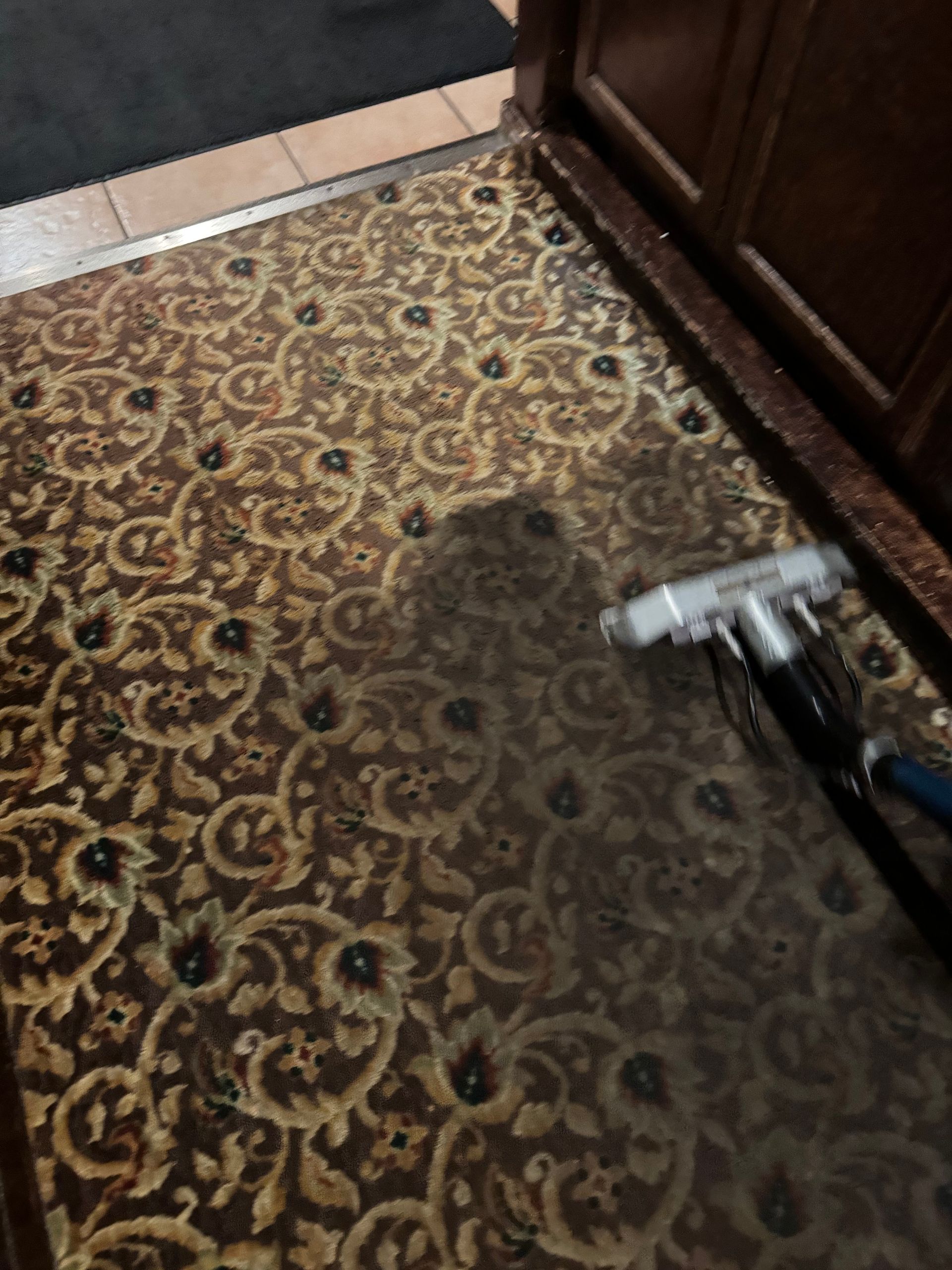 A rug is being cleaned with a vacuum cleaner