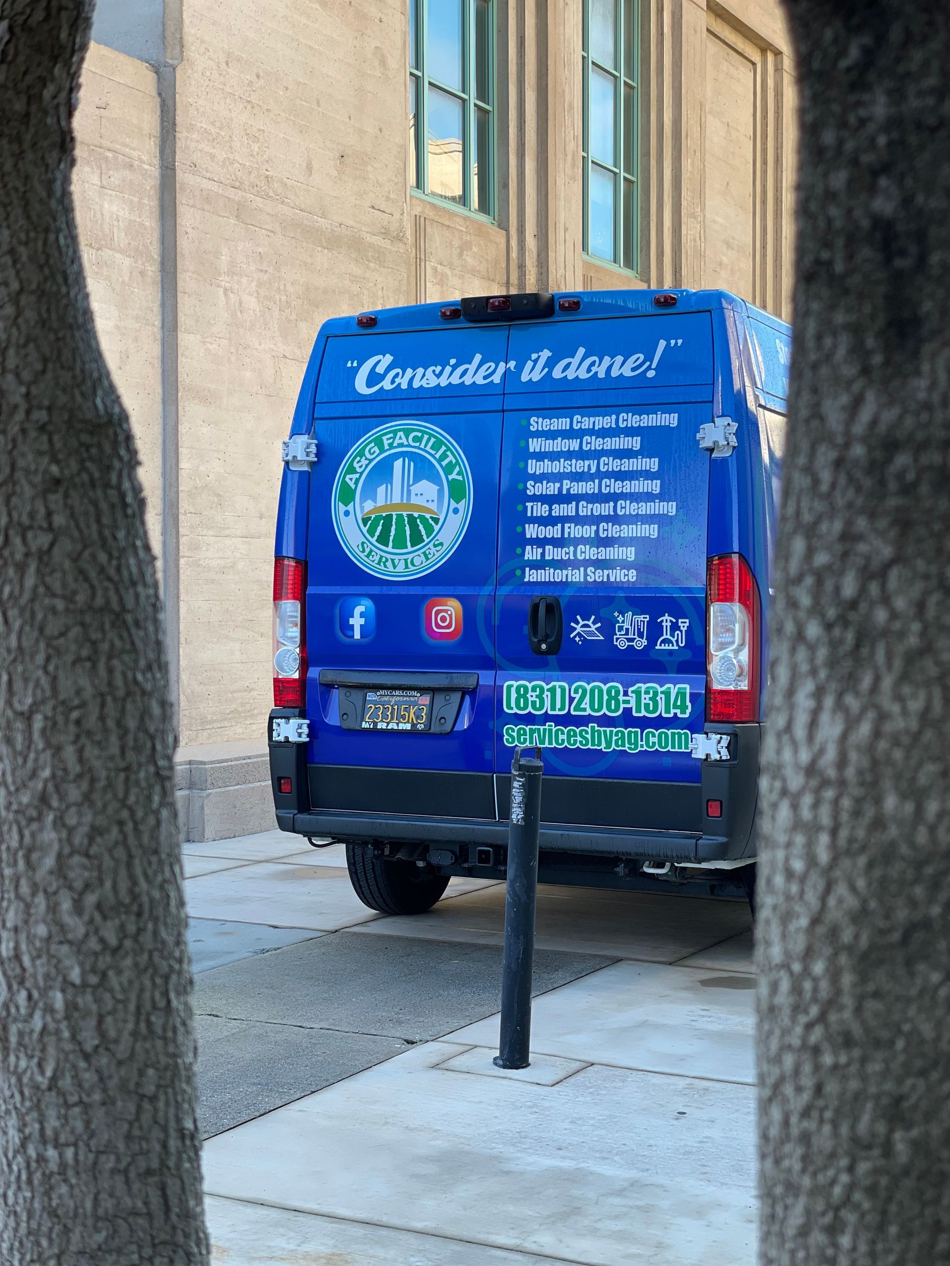 A blue van is parked on the side of the road in front of a building.