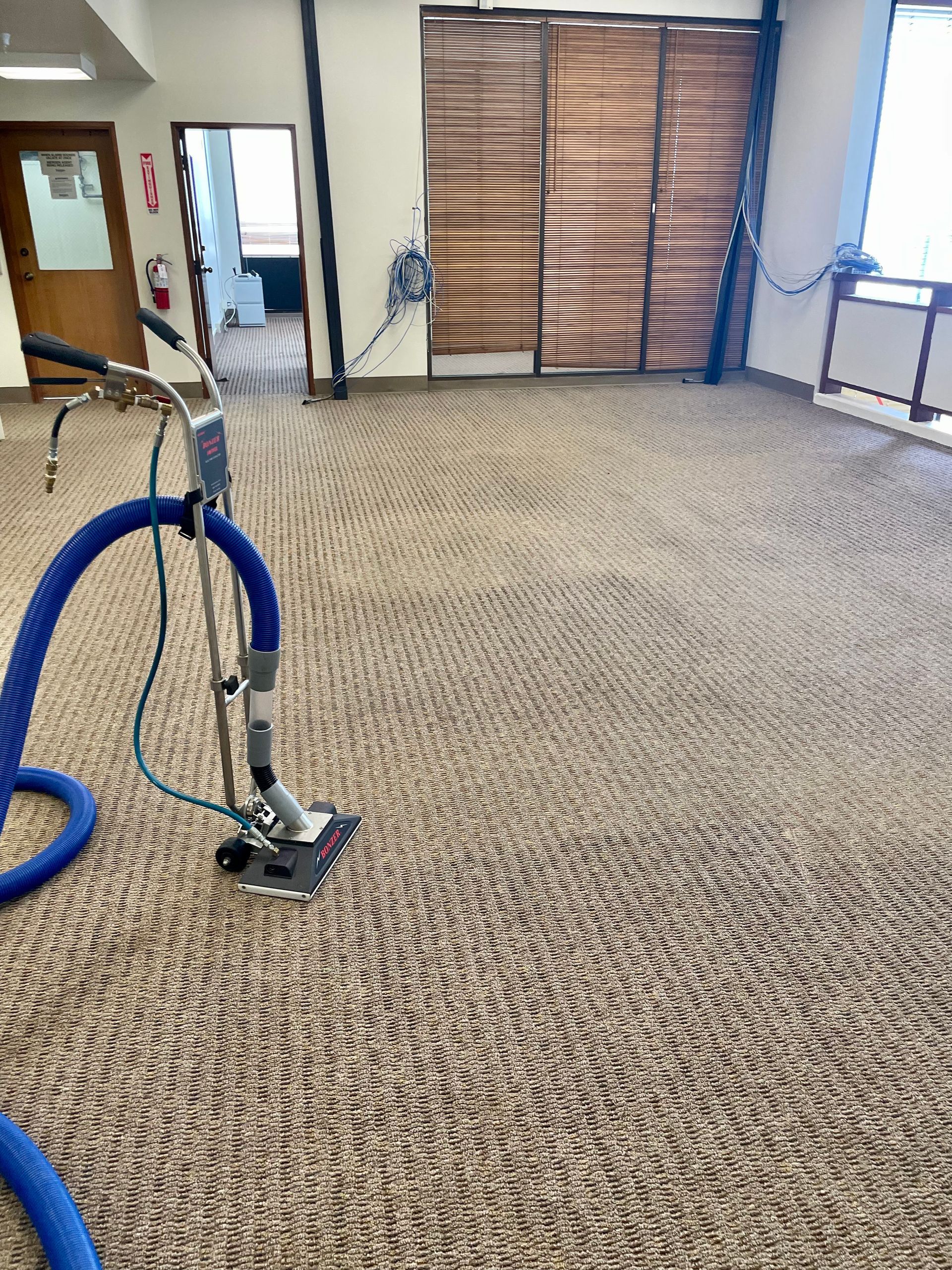A vacuum cleaner is cleaning a carpet in a room.