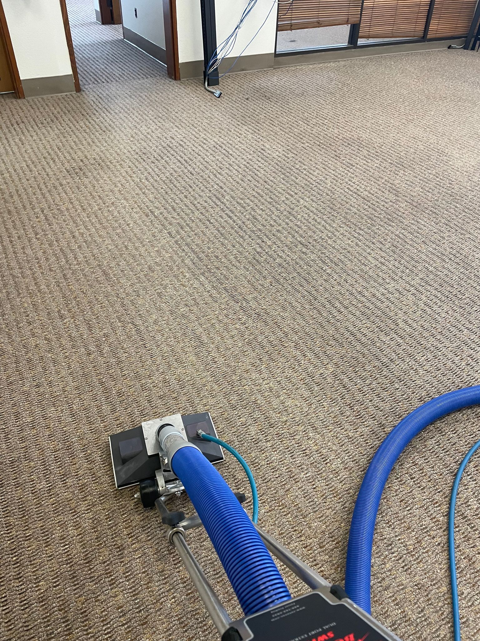 A vacuum cleaner is being used to clean a carpet in a room.