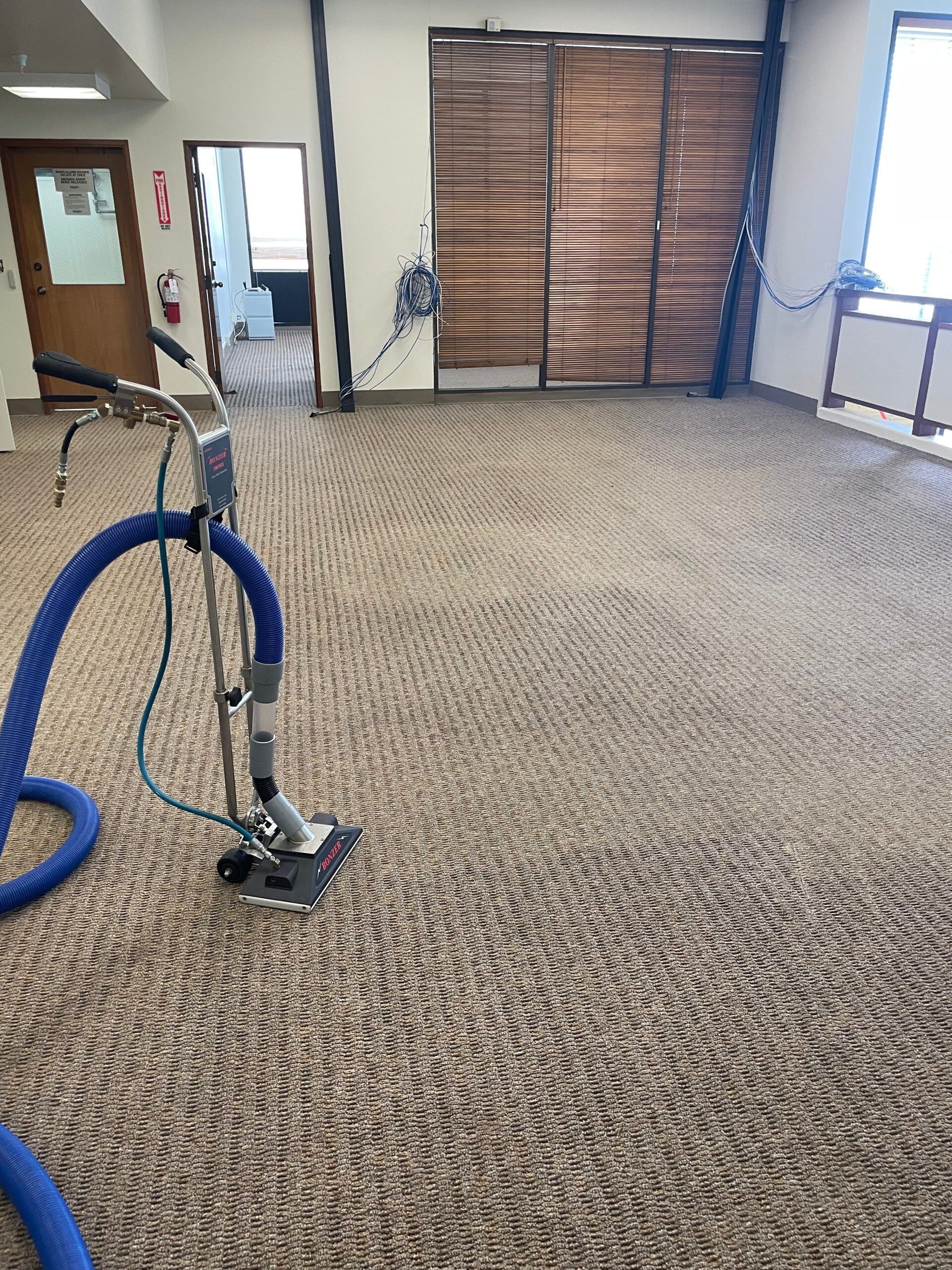 A vacuum cleaner is cleaning a carpet in a room.