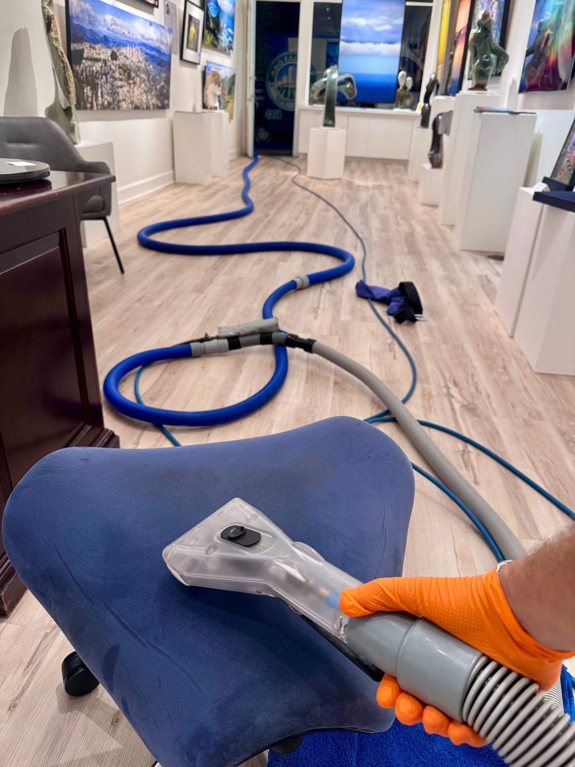 A man is cleaning a leather couch with a vacuum cleaner.