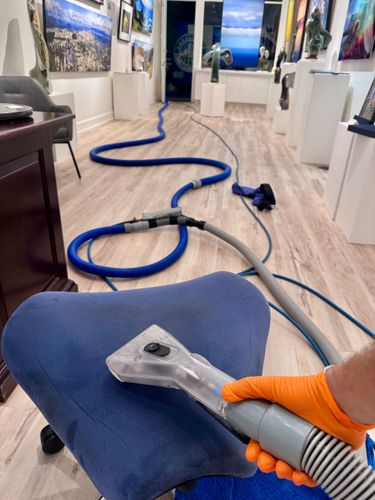 A man is cleaning a leather couch with a vacuum cleaner.