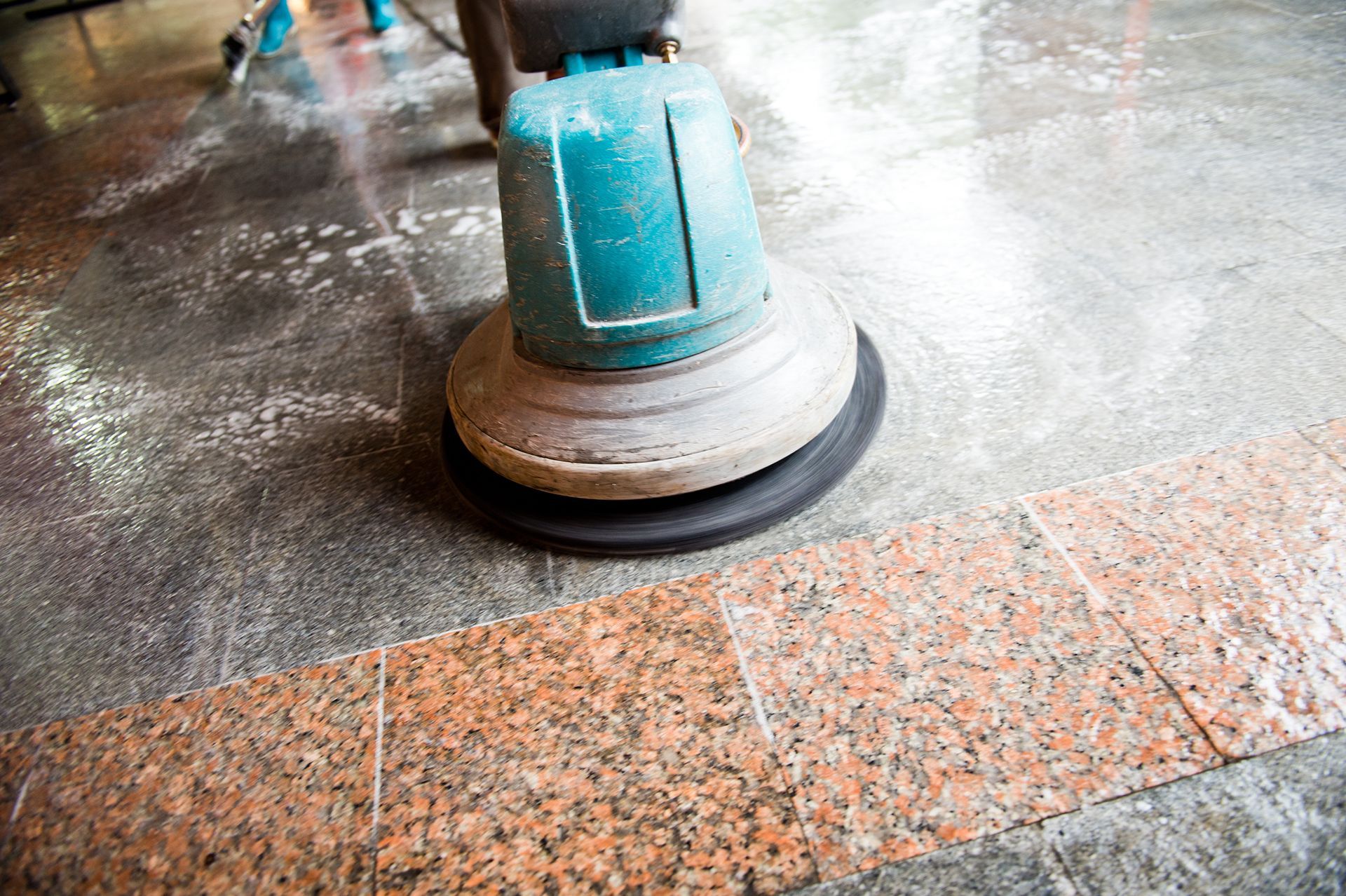 A person is polishing a granite floor with a machine.