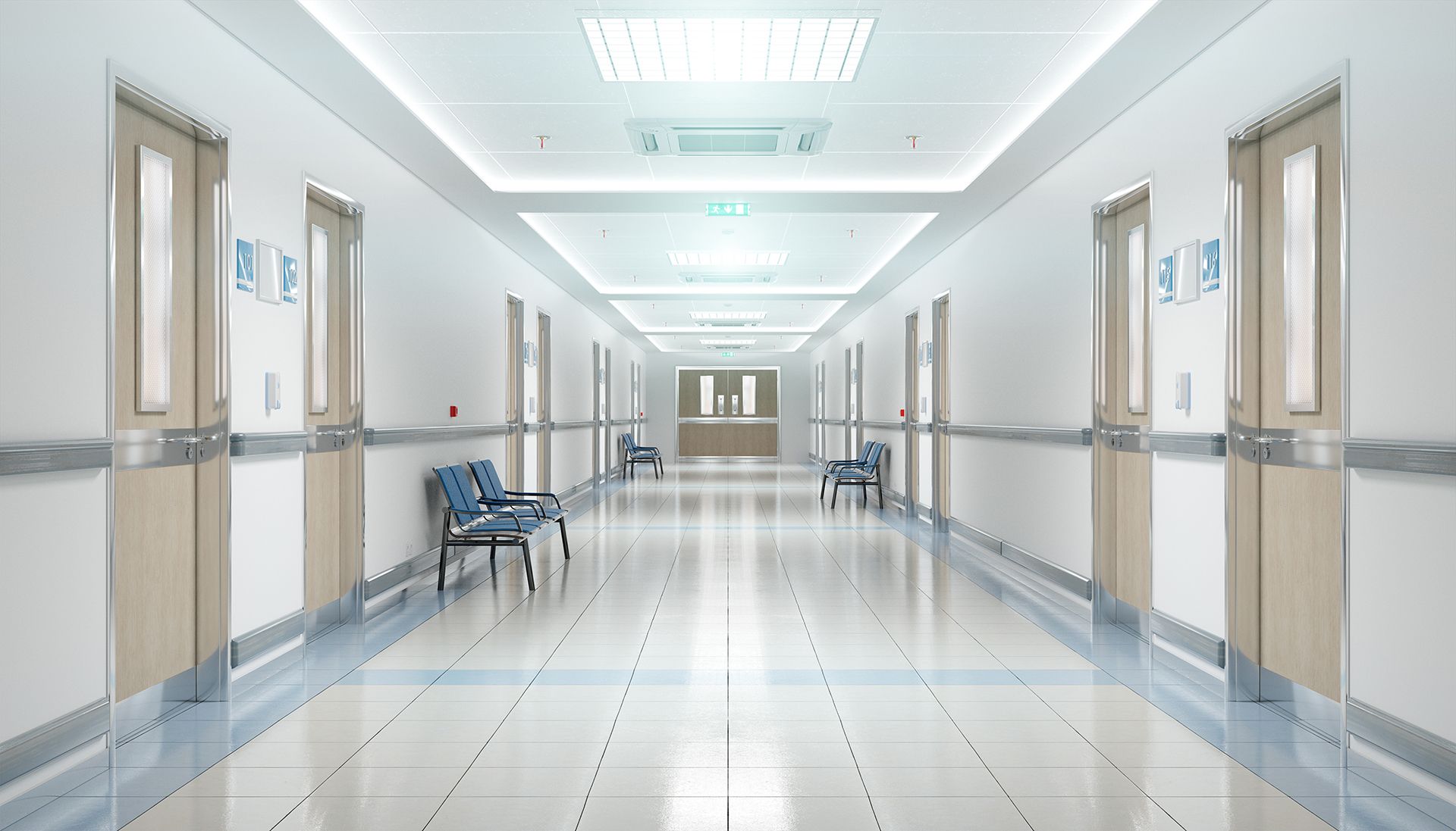 An empty hospital hallway with chairs and doors.