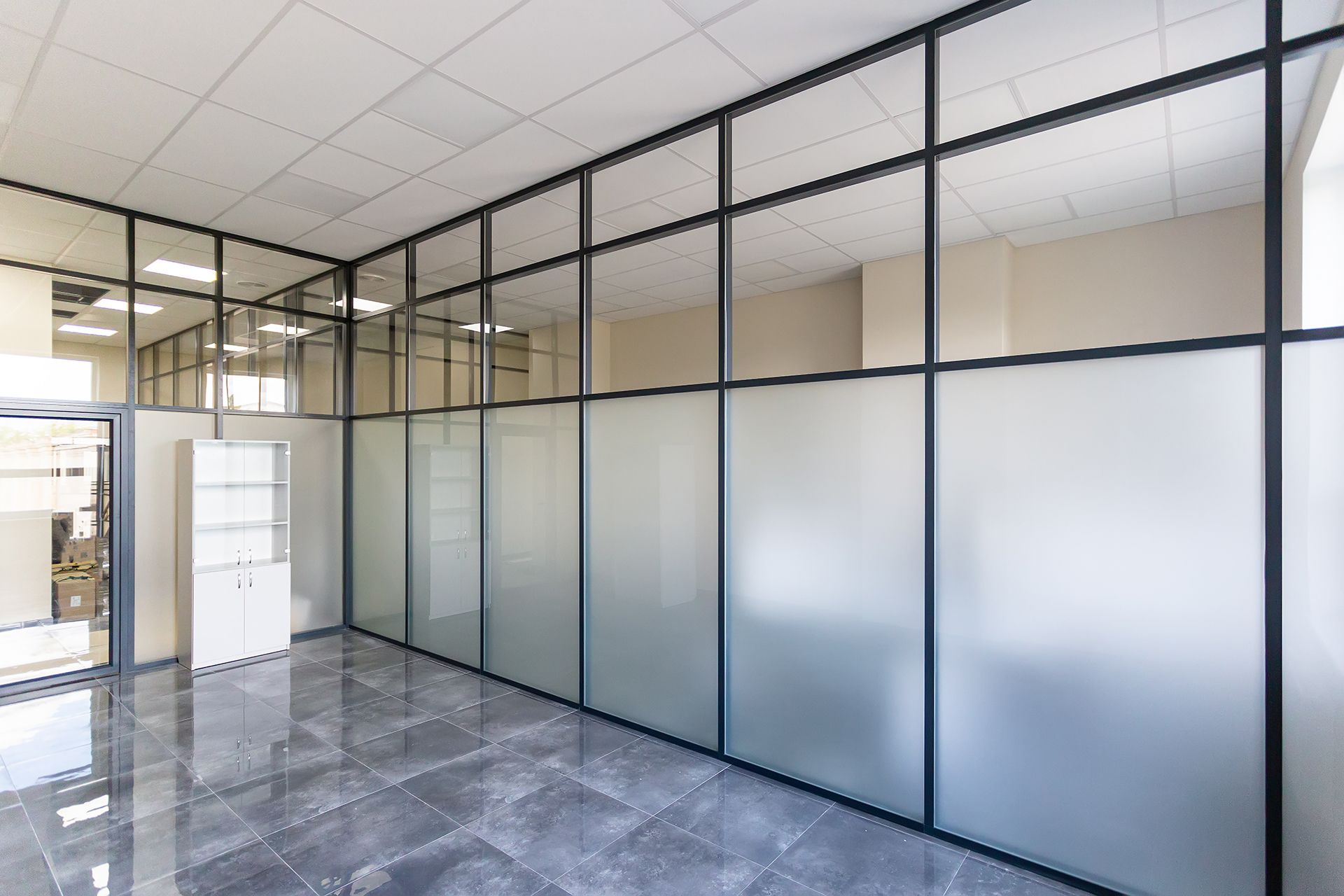 A large empty office with glass partitions and a tiled floor.