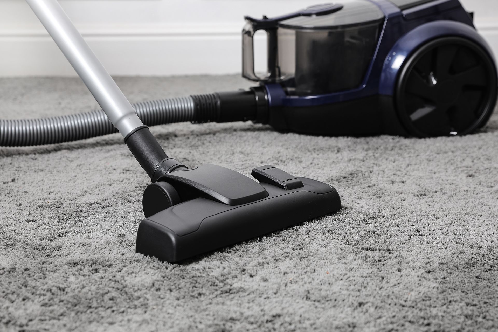 A vacuum cleaner is being used to clean a carpet.