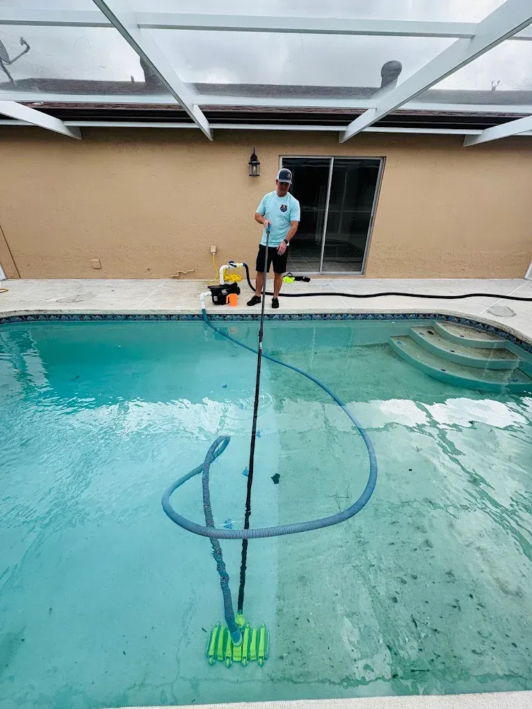 A person is holding a filter in their hand in front of a pool.