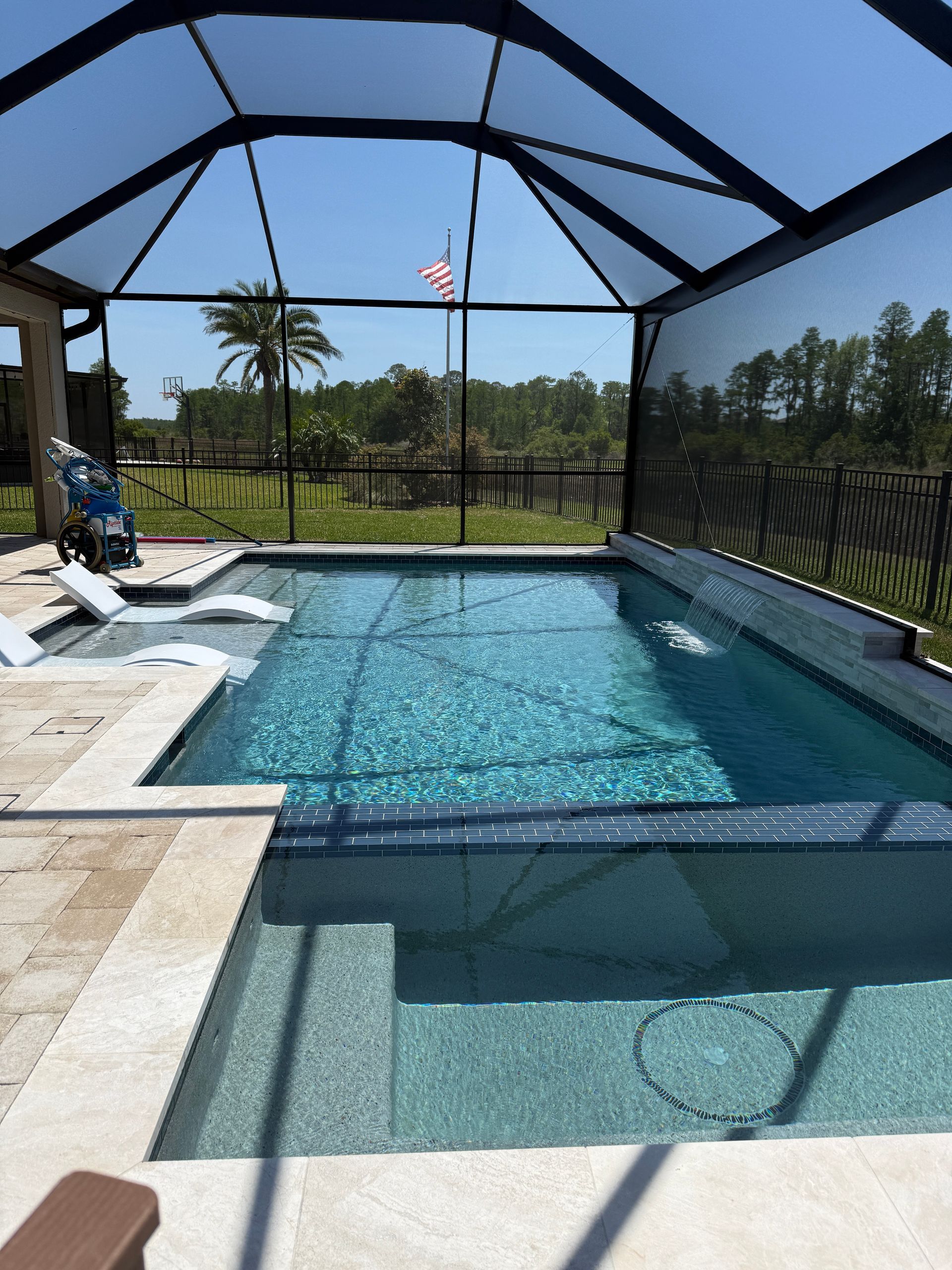 Pool with water jets, screened enclosure, and sunny outdoor setting.