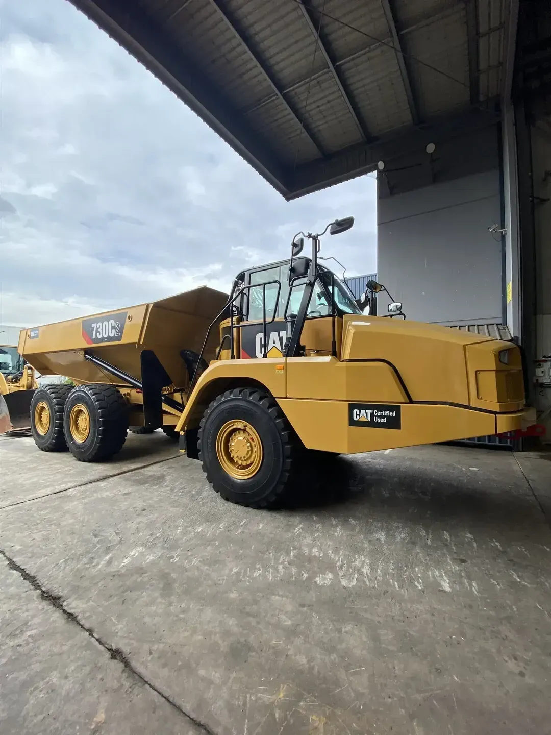 A yellow heavy duty vehicle parked on concrete outside.