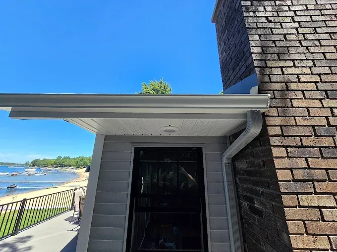 Guttering and roofline of a house overlooking a beach on a sunny day.