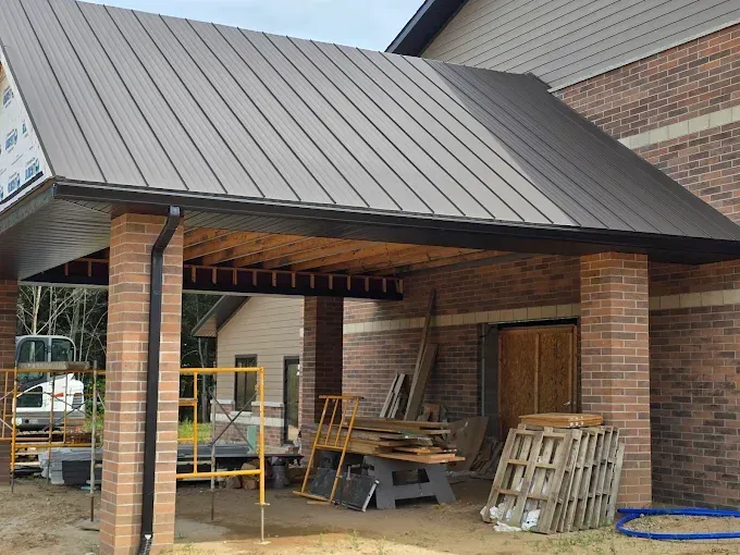 Brick and metal roof entryway of a building under construction, with wood and scaffolding present.
