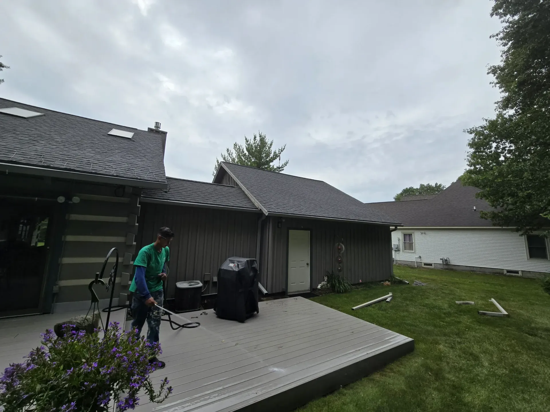 A man is standing on a deck in front of a house.