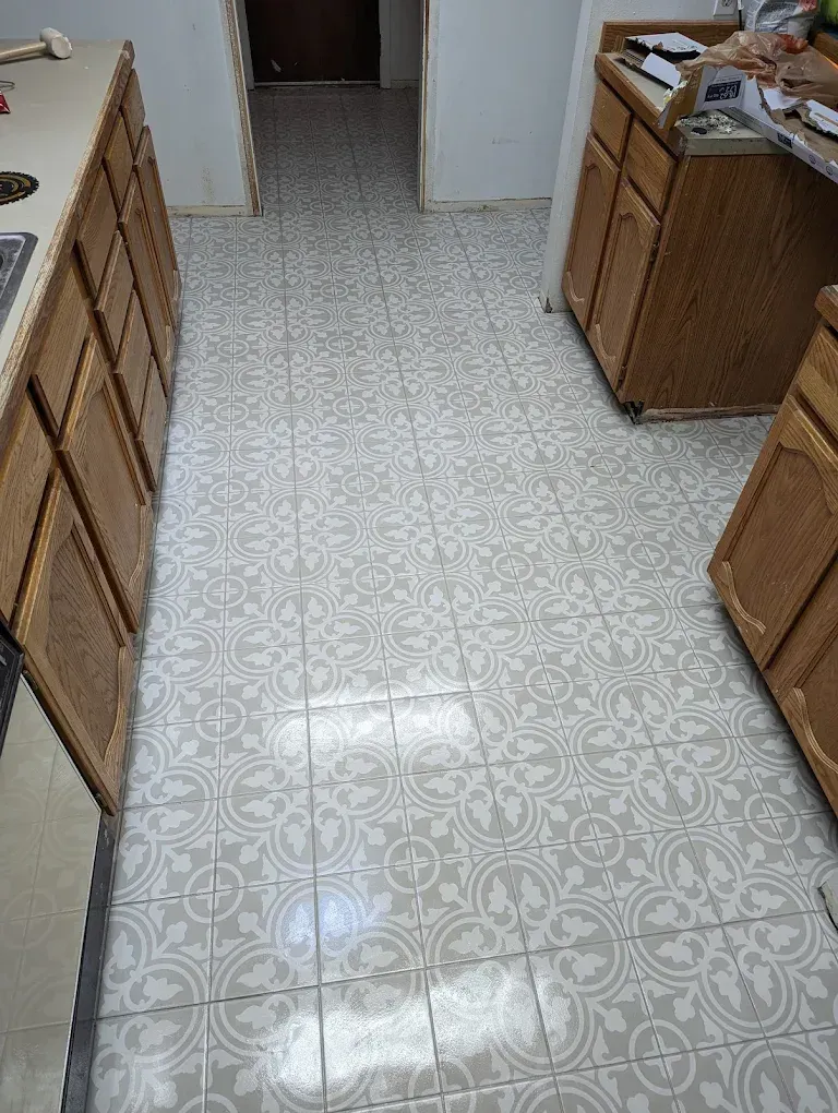 Kitchen floor with patterned gray and white tiles, flanked by wooden cabinets.