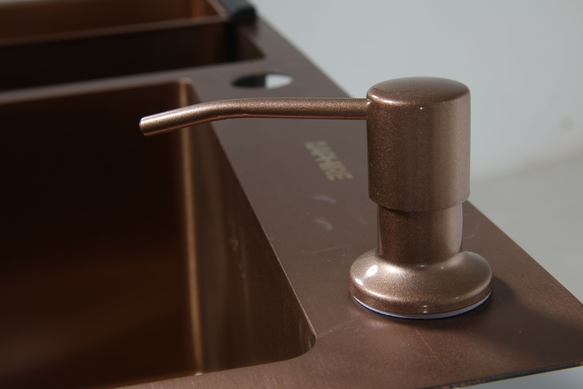 Fregadero de cocina de color cobre con escurridor de platos a la izquierda y grifo a la derecha.