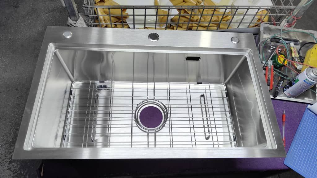 Fregadero de cocina de acero inoxidable con rejilla y accesorios.
