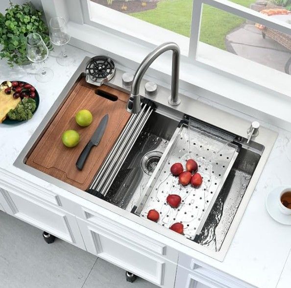 Fregadero de cocina de acero inoxidable con tabla de cortar de madera y escurridor.