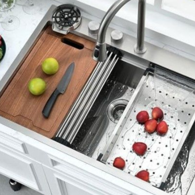 Fregadero de cocina de acero inoxidable con tabla de cortar, productos y grifo.