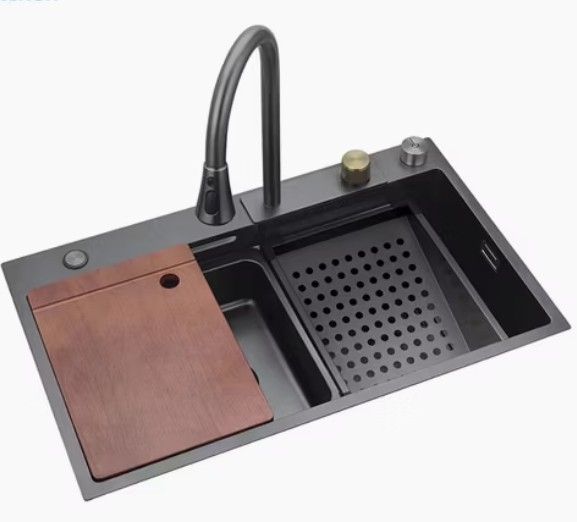 Fregadero de cocina negro con accesorios: tabla de cortar, grifo, desagüe y colador.