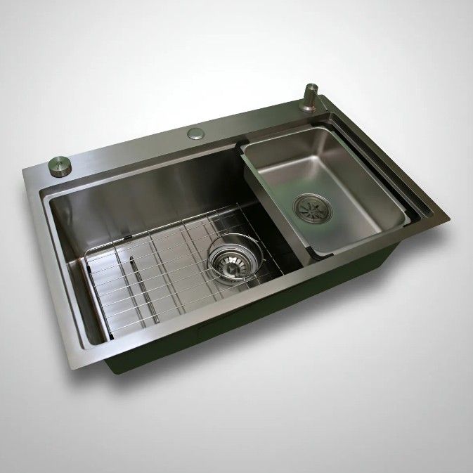 Fregadero de cocina de acero inoxidable con tabla de cortar de madera y escurridor.